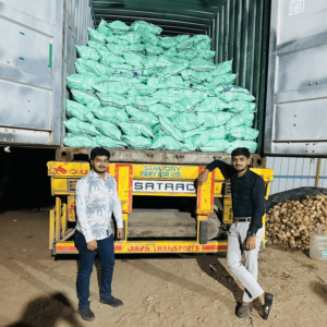 Two men standing in front of a loaded shipping container filled with green export bags, prepared for coconut transportation at a warehouse.