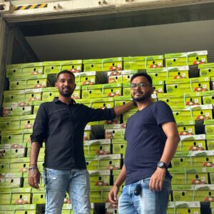 Two men standing in front of stacked vegetables export crates.