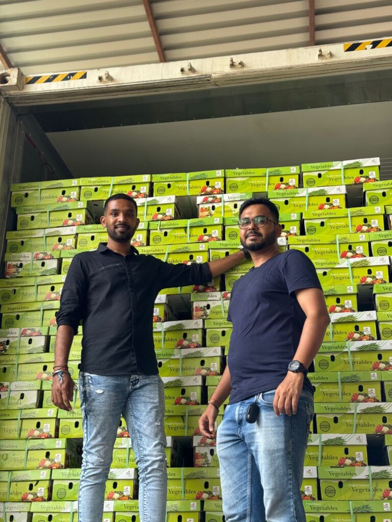 Two men standing in front of stacked vegetables export crates.