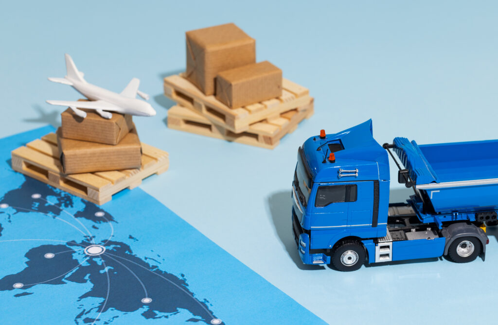 Still life of supply chain management with laptop, smartphone, and miniature shipping cartons