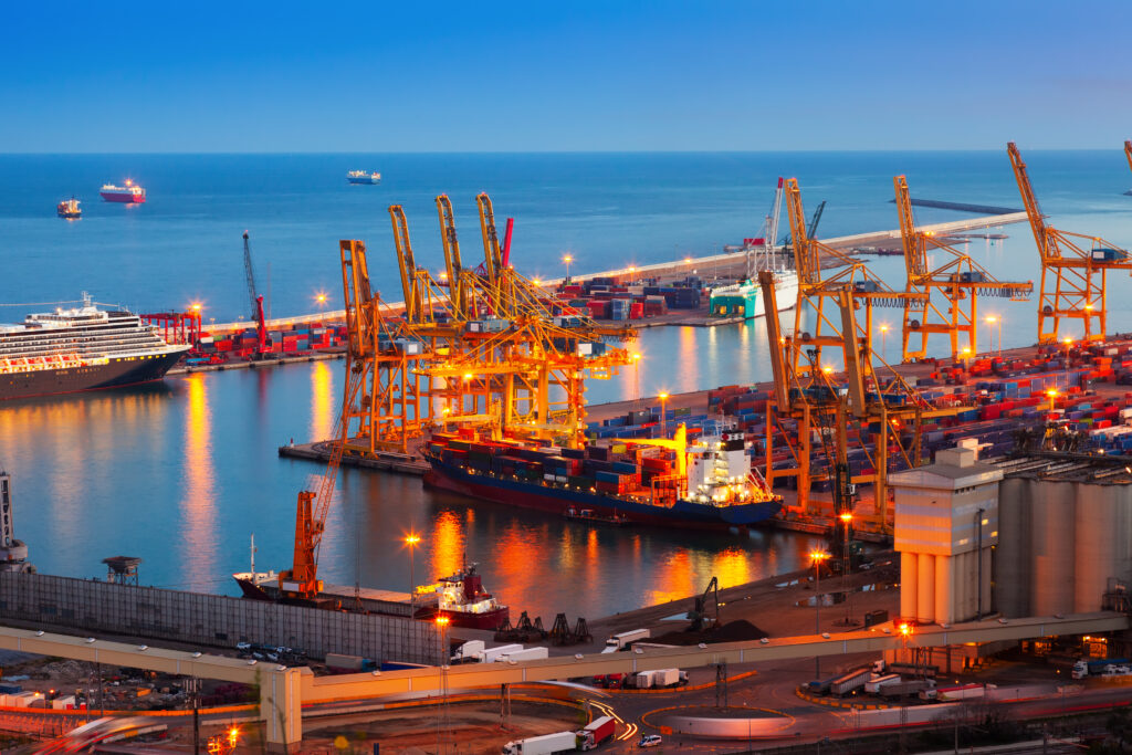 Night view of Port de Barcelona with lit cranes and docked container ships